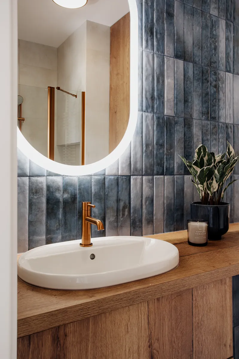 Łazienka z niebieską cegiełką i miedzianą baterią